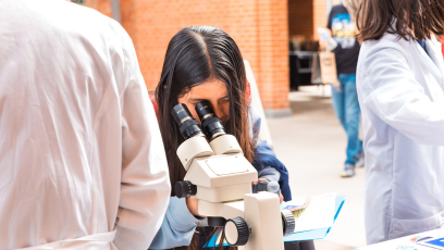 A Hermanas Conference participant at Phoenix College looks into a microscope during this STEAM event