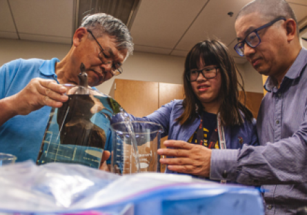 Olneya Fong with her dad and Chemistry Professor Eddie Ong in the Center of Microscopy at Pheonix College, measuring the density of an ironwood carving.