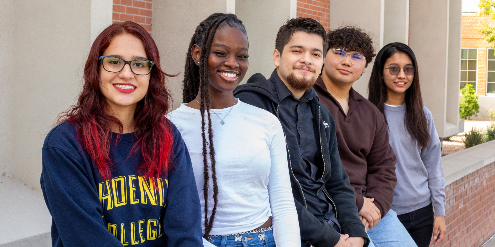 Five students sitting outside the Fannin Library at Phoenix College