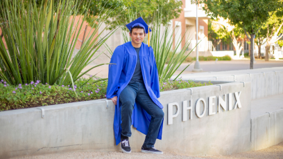 Phoenix College student Elian Jimenez on campus in his blue graduation cap and robe