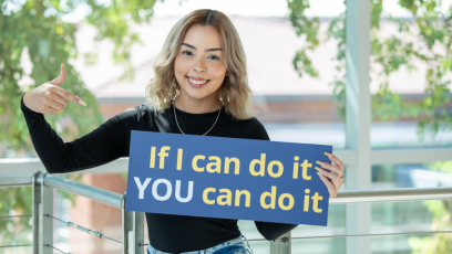 Jasmin in the Dalby Building holding up a sign that states, "If I can do it YOU can do it"