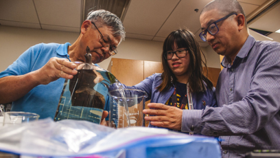 Olneya Fong with her dad and Chemistry Professor Eddie Ong in the Center of Microscopy at Pheonix College, measuring the density of an ironwood carving.