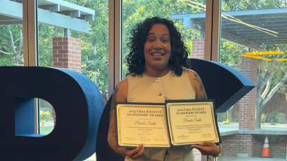 PC student Pamela Smith stands in the Student Union holding up two awards for her leadership