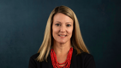 Headshot of Dr. Heather Kruse in a black jacket and a multi-strand red beaded necklace.  