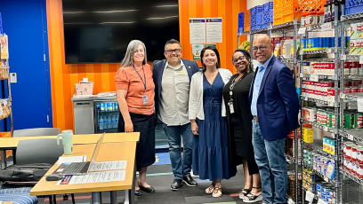 Phoenix College staff and Smart & Final employees meet inside the Bumstead Resource Room among shelves of canned goods and other food supplies for students.