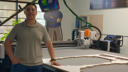 Cesar Salas standing inside his workshop smiling at camera