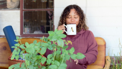 Phoenix College Yoga Instructor Ashley Burns sips tea on a bench with her yoga mat, bringing mindfulness to each moment.