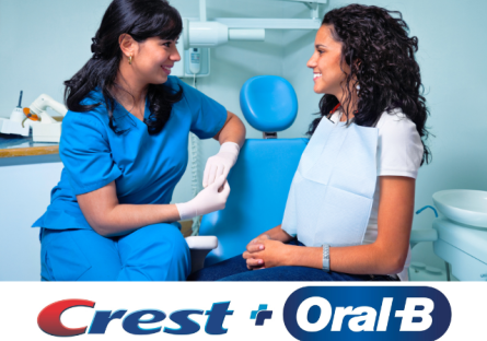 Crest and Oral B logo with Hispanic dental assistant meeting with patient image