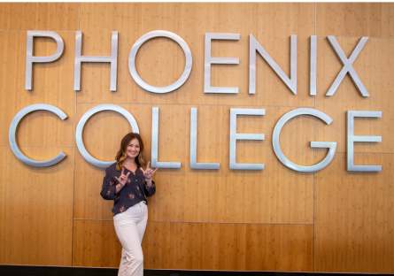 Jillian Deaton, an ASL interpreter stands in front of a Phoenix College sign on campus