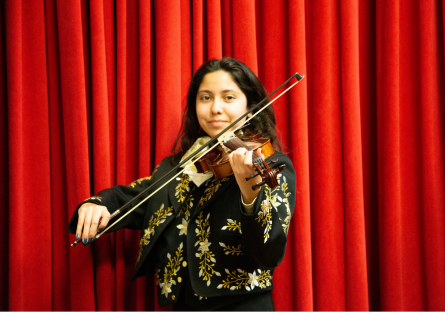 A mariachi violinist wearing a traditional traje plays her violin standing up