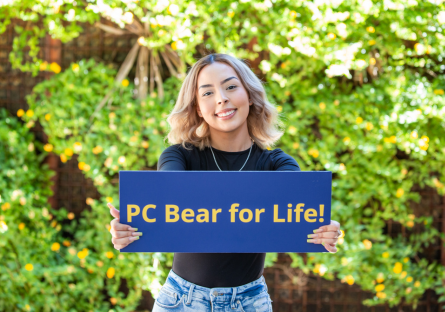 Jasmin holding up a sign that says "PC Bear for Life!"