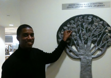 Phoenix College alumnus Kevvin Taylor stands next to PC's Black Student Union Living Legend award tree.