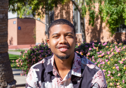 Phoenix College student and Black Student Union President Javyn Booth sits on campus in a black shirt printed with pink roses