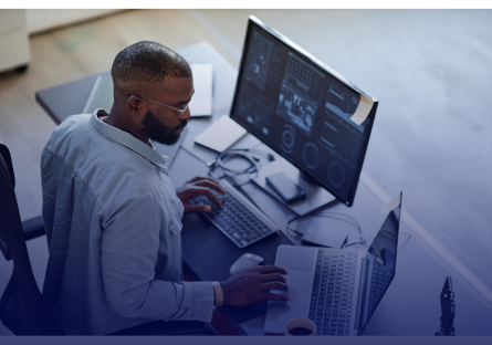 African American business man working at a laptop with multiple screens