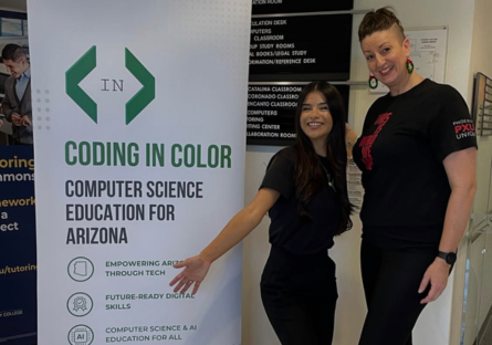 Diana Lee Guzman, founder of Coding in Color and Carl Hayden High School alumna, stands between a Coding in color Banner with the words "Coding in Color: Computer Science Education for Arizona" and a Phoenix Union High School Teacher wearing a PXU t-shirt that says "This is Who We Are." 