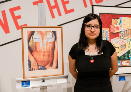 Phoenix College student Jade Trujillo, stands to the right of her work, "Sweat Tour," showing the image of a female torso in a bikini top, which won her a Vanguard Award for Digital Art