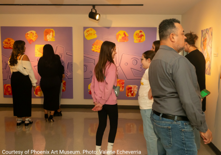 Viewers look at the work in the Cultural Identity exhibition during the opening reception 