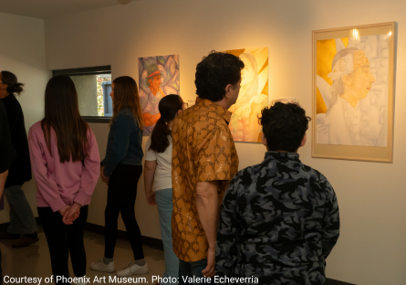 Viewers look at the work in the Cultural Identity exhibition during the opening reception 