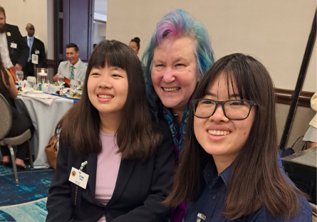 Olina sits at the All-AZ ceremony with her sister Olneya Fong with PTK advisor Amy MacPherson visible between them