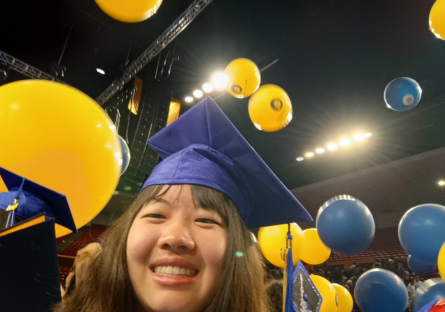 A headshot of Olina Fong shows her wearing a blue graduation cap with blue and yellow balloons suspended in the air around her