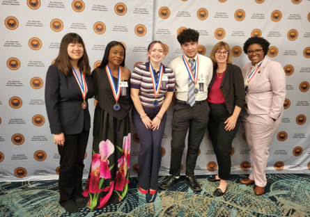 Olina Fong stands on the left with other PTK Regional Officers in from of the All-AZ ceremony step and repeat backdrop 