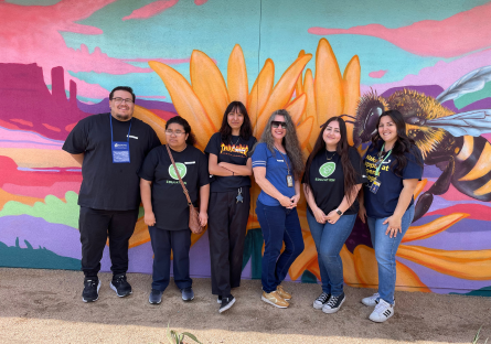 Phoenix College Education Director Kat Valdivia stand in front of mural with five Reading Volunteers who read stories to students at Encanto Elementary