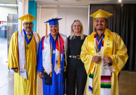 Luis Duque stands in a yellow cap and gown next to Executive Provost and Vice Chancellor Dr. Kimberly Britt dressed in black, Governing Board student representative Pamela Smith in her blue cap and gown and PC Student Senator Ludwig Chavez in his yellow cap and gown at PC's commencement ceremony