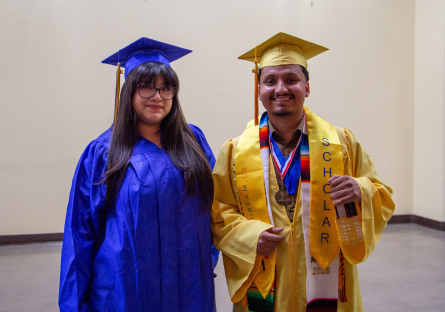 Luis Duque stands in his yellow cap and gown next to PC United President Galilea Guzman in her blue cap and gown at PC's Class of 2026 commencement ceremony