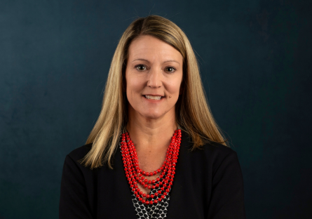 Headshot of Dr. Heather Kruse in a black jacket and a multi-strand red beaded necklace.  
