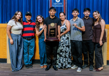 Men's soccer all-star and team captain Cruzerio Cruz hold the champion trophy with his family standing next to him