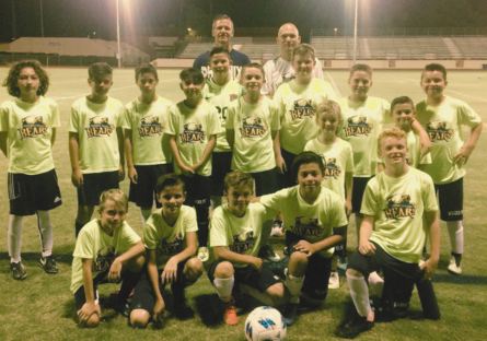 A picture of National Championship team members Jack Cameron, Landon Vree, Andre Miyazaki, and T.J. Pompa with other Little Bears dressed in florescent shirts on the field