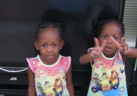 A picture of Shadé and Sy'nai as small children dressed in the same "Flower Power" shirt with Sy'nai holding up peace fingers in front of her face