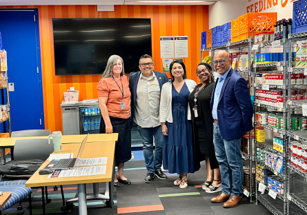 Phoenix College staff and Smart & Final employees meet inside the Bumstead Resource Room among shelves of canned goods and other food supplies for students.
