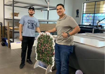Cesar posing with a finished tree product with his employee