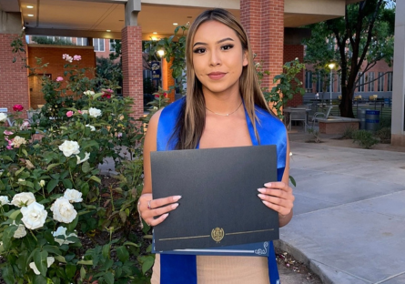 Alyssa posing with her diploma in Pastor Plaza on Phoenix College campus