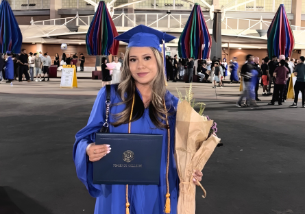 Alyssa in her cap and gown posing with her diploma outside the Veteran's Memorial Coliseum for PC's Commencement