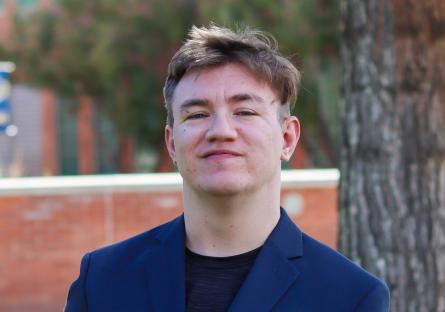a young man poses for a picture in front of a library