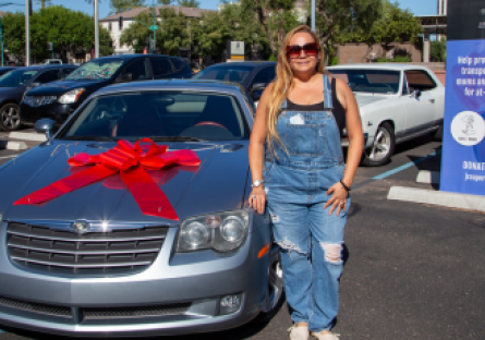 Phoenix College Nursing Student Jacquelina Reyes stands next to a the car she received as part of a JC Supercar Giveaway