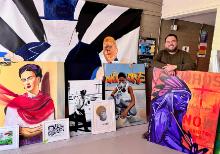 Artist Francisco Garcia in his Grand Avenue studio standing among a display of his art in frames, on canvas, etc.