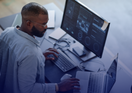 African American business man working at a laptop with multiple screens