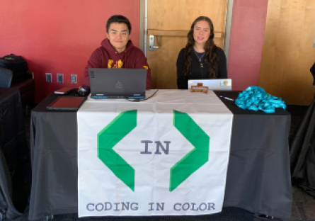 Kenneth Ho and Shelby Alonso sit at a table with a Coding in Color banner ready to welcome high school student to the Day of Compute at Phoenix College