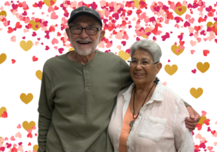 Former Phoenix College students Pat Murphy and Angela Perea-Murphy stand side by side, Pat's arm around Angela with a digital backdrop of hearts