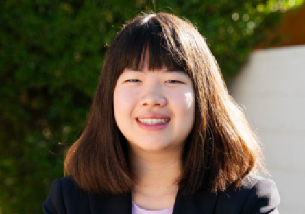 Headshot of Olina Fong on campus with a white background and triangle of green foliage behind her