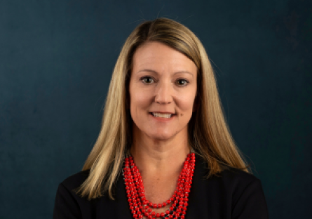 Headshot of Dr. Heather Kruse in a black jacket and a multi-strand red beaded necklace.  
