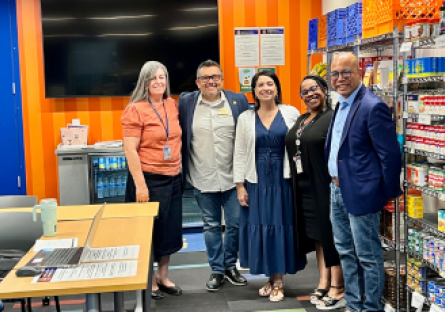 Phoenix College staff and Smart & Final employees meet inside the Bumstead Resource Room among shelves of canned goods and other food supplies for students.