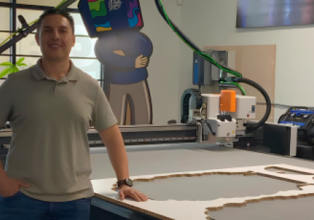 Cesar Salas standing inside his workshop smiling at camera