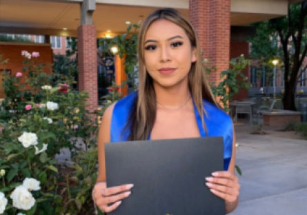 Alyssa posing with her diploma in Pastor Plaza on Phoenix College campus