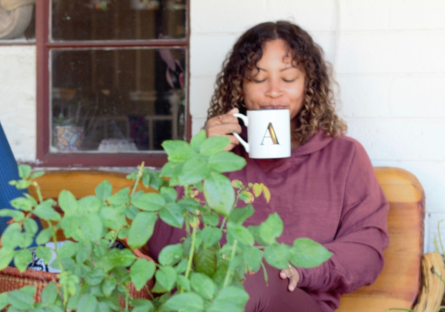 Phoenix College Yoga Instructor Ashley Burns sips tea on a bench with her yoga mat, bringing mindfulness to each moment.