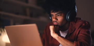 Male student in red shirt staring at his laptop