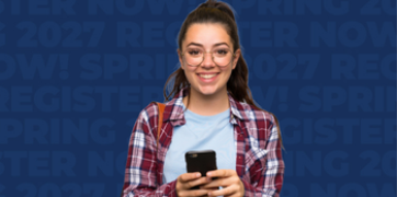 Female student holding cell phone smiling into camera with blue background